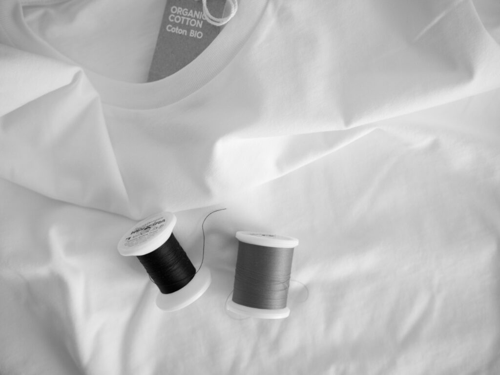 T-shirt en coton bio et bobines de fil noir et rouge, utilisés pour la broderie artisanale des vêtements Nozomu Collections